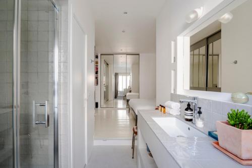 une salle de bain blanche avec un lavabo et une douche dans l'établissement Veeve - The Old Printworks, à Paris