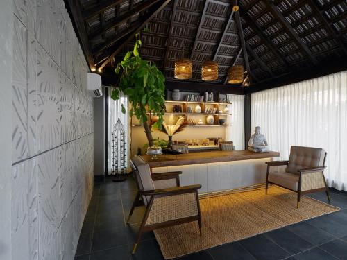 a kitchen with a counter and two chairs and a plant at Red Thread Morjim in Morjim
