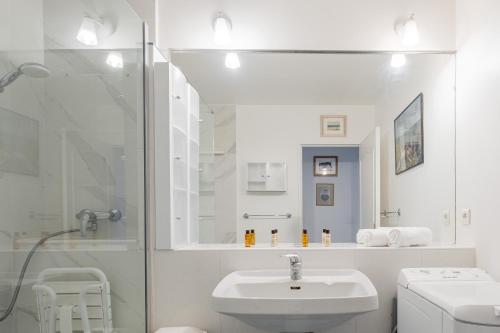 biała łazienka z umywalką i prysznicem w obiekcie Veeve - Honeybee Haven w Paryżu