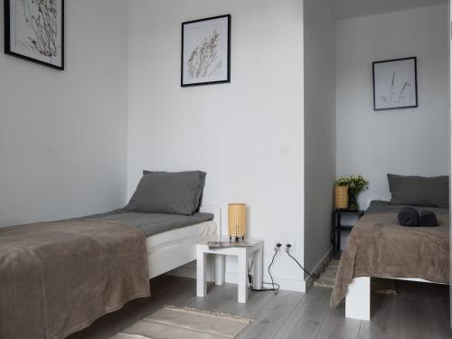 - une chambre blanche avec 2 lits et une table dans l'établissement Apartament Clever 2 Kamienica Grochów, à Varsovie