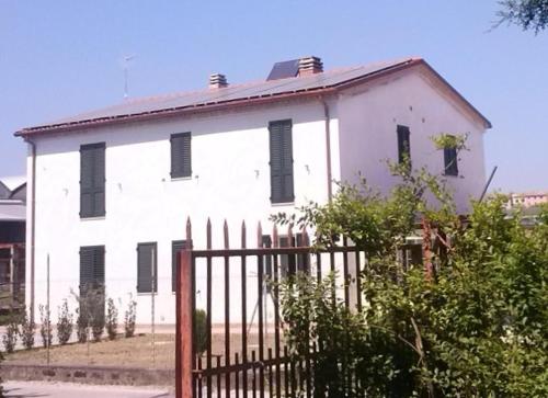 a white house with black shuttered windows and a fence at B&B Verziere in Iesi