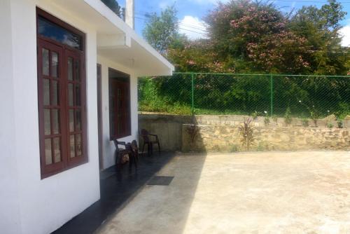 a porch of a house with a door and a fence at The Dew Drop Villa in Nuwara Eliya