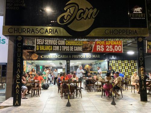 a group of people sitting at tables in a restaurant at Ed Parati 2 quartos Praia do Morro - Guarapari in Guarapari