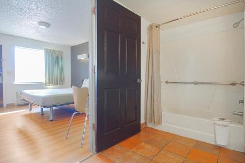 Habitación con baño con bañera y puerta. en Studio Inn Extended Stay Oklahoma City Airport by OYO, en Oklahoma City