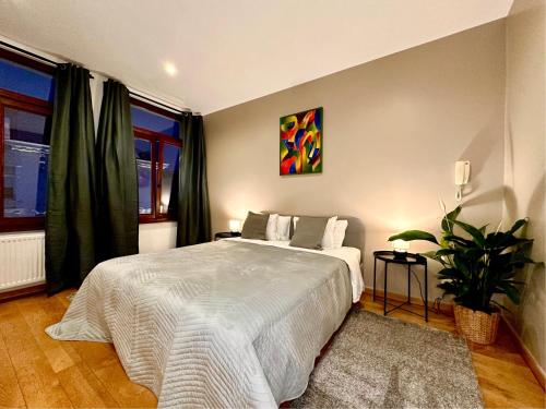 a bedroom with a large white bed and a plant at Luxury Suites Museum by Rikas Hotels in Antwerp