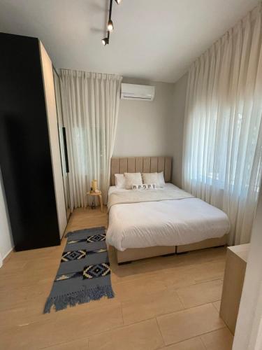 um quarto com uma cama branca e um tapete azul em شقة مريحةمع إطلالة ،أثاث بوهيمي em Amã