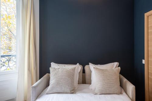 uma cama com almofadas brancas e uma parede azul em The Blue Suite Downtown Montmartre em Paris