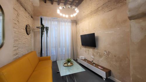 sala de estar con sofá amarillo y TV en RentalSevilla Cardenal Cervantes, en Sevilla