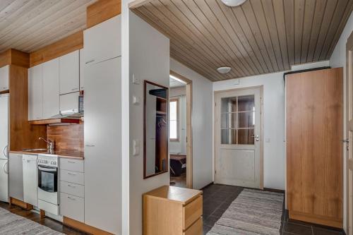 a kitchen with white cabinets and a wooden ceiling at Viihtyisä lomahuoneisto Rukalla! in Kuusamo