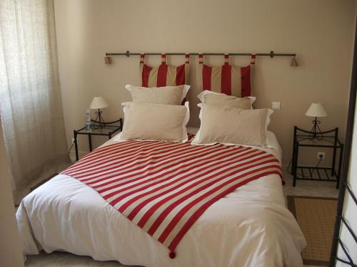 a large bed with a red and white striped blanket at Mas De Gorjan in Clermont-lʼHérault