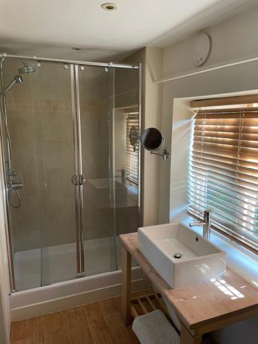 La salle de bains est pourvue d'une douche et d'un lavabo blanc. dans l'établissement Little Barn, à Dorchester