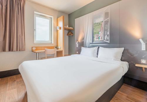 een hotelkamer met een groot bed en een bureau bij B&B HOTEL Mulhouse Ile Napoléon in Illzach