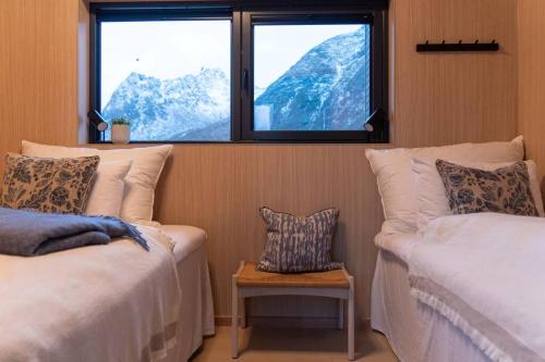a room with two beds and a window with mountains at Luksushytte med Jacuzzi, Summer&Winter Retreat in Lyngværet