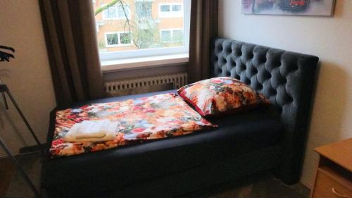 a black bench with a pillow and a window at Döhren - 2 Single rooms in Hannover