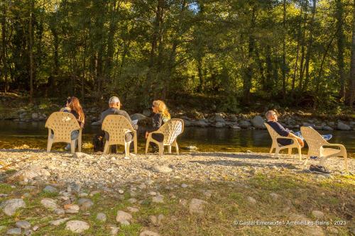 un groupe de personnes assises sur des chaises au bord d'une rivière dans l'établissement Appart'Hotel Castel Emeraude, Charme et Caractère, à Amélie-les-Bains-Palalda