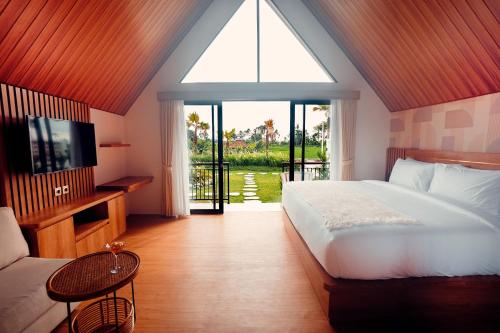 a bedroom with a bed and a tv and a window at Padi Villas by Aayan in Canggu