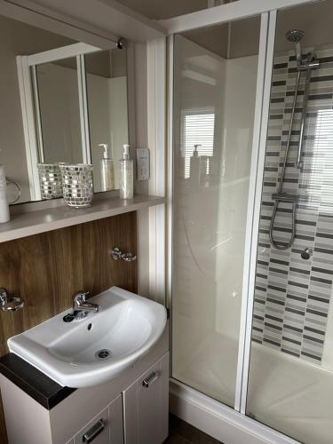 a bathroom with a white sink and a shower at Presthaven sands P&Ts home from home in Talacre