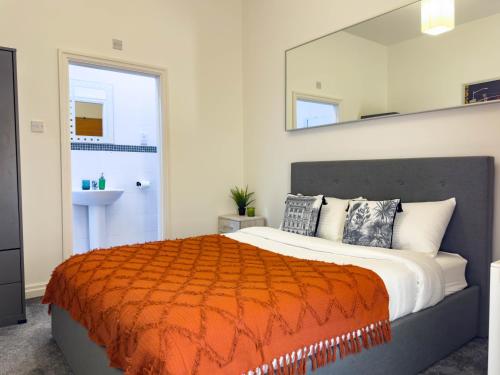 a bedroom with a large bed with an orange blanket at 2 Bed - Close to LBU, Headingley Stadium and YCC in Leeds