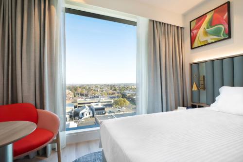 a hotel room with a bed and a large window at Holiday Inn & Suites Geelong by IHG in Geelong