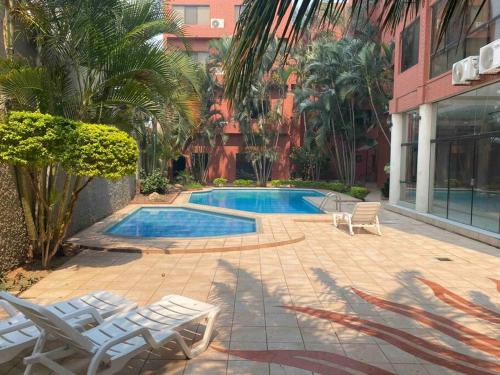 a swimming pool with lounge chairs next to a building at Departamento de 2 habitaciones in Santa Cruz de la Sierra