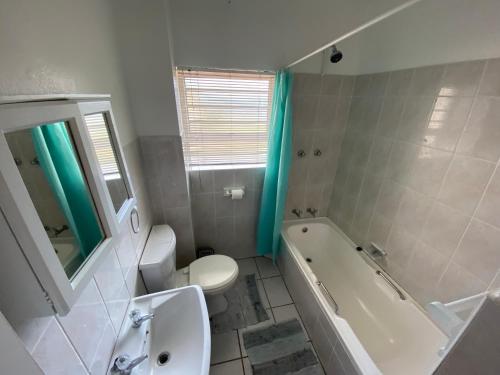 a bathroom with a toilet and a tub and a sink at Uvongo Square 2 in Margate