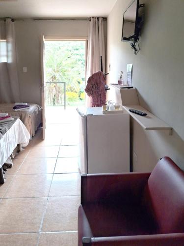 a living room with a couch and a room with a window at Pousada Juriti - Eco Hotel in São Roque