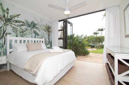 a bedroom with a white bed and a sliding glass door at 210 Breakers Resort Umhlanga Rocks in Durban