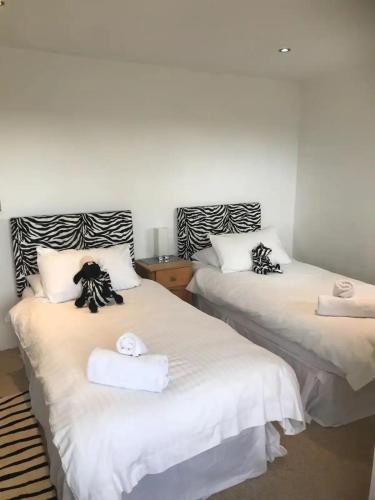two beds with towels on them in a room at Claremont Beach House in Greatstone