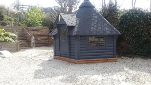 a blue dog house with a black roof at Claremont Beach House in Greatstone