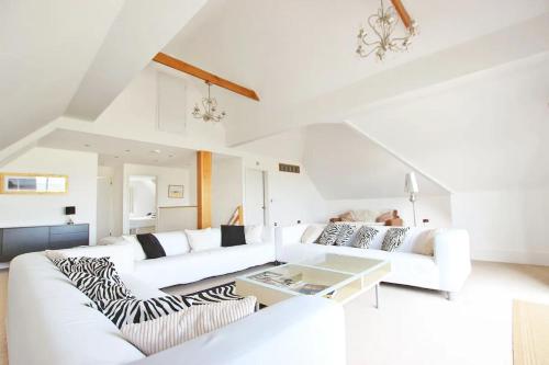 a white living room with two white couches and a table at Claremont Beach House in Greatstone