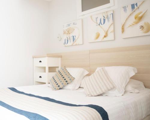 a bedroom with a bed with white sheets and pillows at Hotel La Ciotat - A deux pas de l'eau in La Ciotat