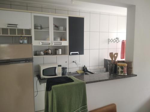 a kitchen with a counter with a microwave and a sink at Apartamento bem localizado in Franca