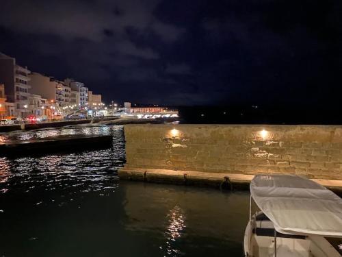 un bateau est amarré dans une rivière la nuit dans l'établissement Beach House. Live, experience sea, à San Pawl il-Baħar