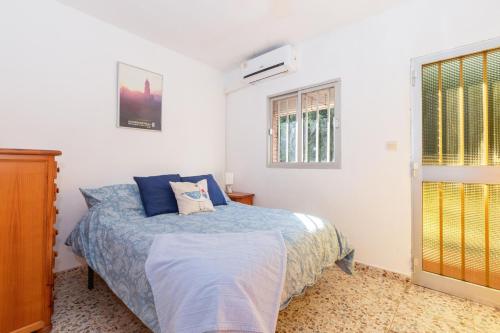 a bedroom with a bed with blue sheets and a window at Casa Coral Beach in Málaga