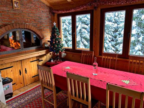 a dining room with a red table and a fireplace at Vikendice Jahorinska Dvorišta in Pale