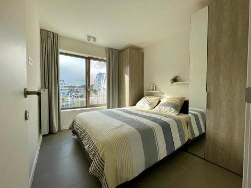 a bedroom with a bed and a large window at West Bay Apartments in Middelkerke