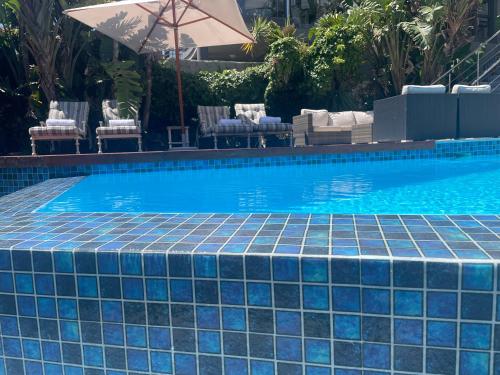 a swimming pool with a blue tile floor and an umbrella at Gull on the Bay Boutique Guest House in Bloubergstrand