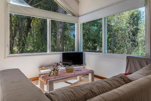 een woonkamer met een bank en 2 grote ramen bij Happy Host-Casas Cruz del Sur in Villa La Angostura