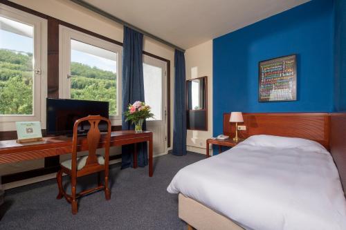 Habitación de hotel con cama y escritorio con ordenador en Sauerland Alpin Hotel, en Schmallenberg