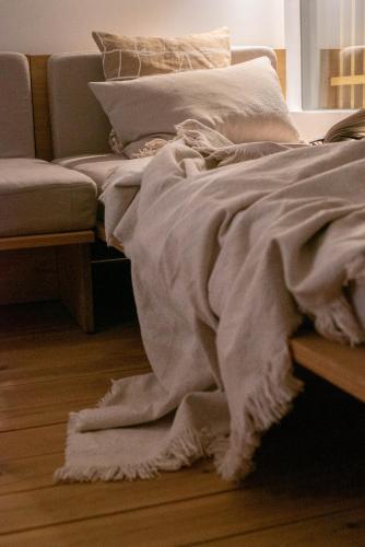 a bed with a blanket on the floor next to a couch at hejHUS w Strzyżach in Strzyże
