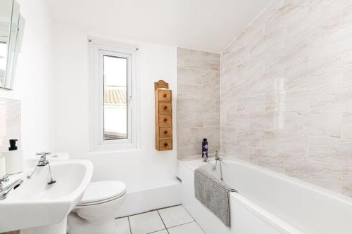 uma casa de banho branca com uma banheira, um WC e um lavatório. em AJ's Stays - FREE WIFI - FREE PARKING - GARDEN - SLEEPS UP TO 7 - 4 BEDS em Bristol