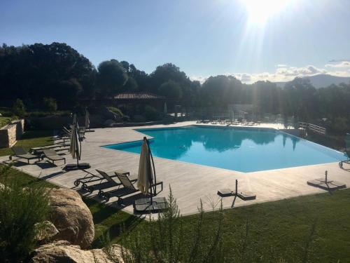 a large swimming pool with chairs and umbrellas at Domaine d'Arca - Flaubert 11 - 4 pers - étage 1 in Porto-Vecchio