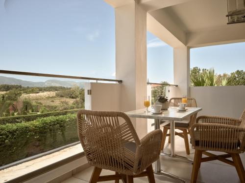 une salle à manger avec une table, des chaises et une grande fenêtre dans l'établissement Marelen Hotel Zakynthos, à Kalamaki