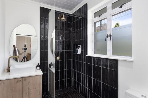 a black tiled bathroom with a sink and a mirror at Chic Studio Apartment Mountain views Gardens in Cape Town