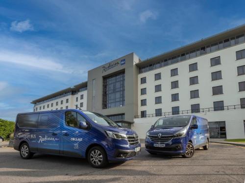 two blue vans parked in front of a building at Radisson Blu Hotel Dublin Airport in Cloghran