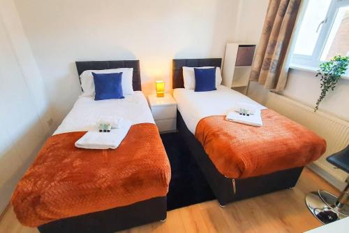 twee bedden in een kamer met blauwe en oranje lakens bij Captivating 4-Bed House in Cheltenham in Cheltenham