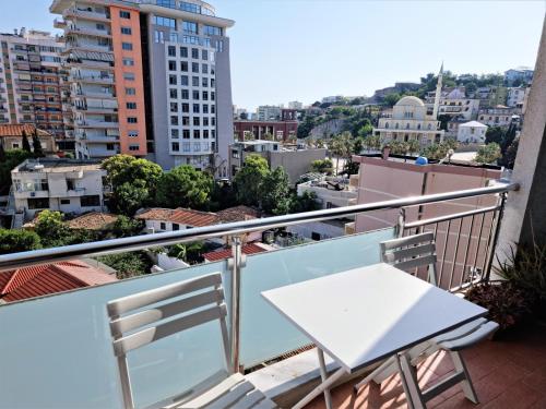 een witte tafel en stoelen op een balkon met gebouwen bij Apartment 13 - Your Perfect Stay in Durres City in Durrës