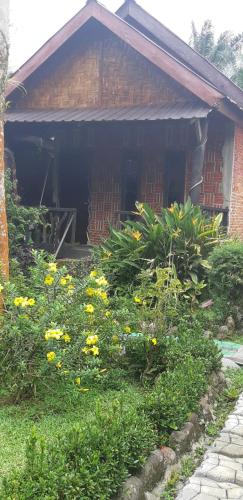 a garden with yellow flowers in front of a house at Mountain View Cottages & Villa Tangkahan in Tangkahan