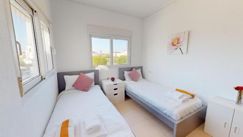 two beds in a room with two windows at La Torre Villa Bacalao - A Murcia Holiday Rentals Property in Roldán