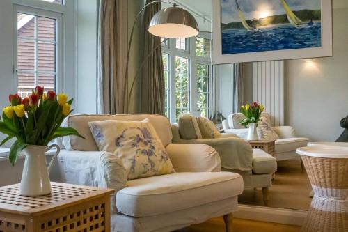 a living room with a couch and chairs and flowers at 40 Trelawny Way in Bembridge